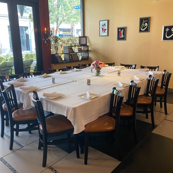 A long dining table with white tablecloths and dark chairs, set for a large group.