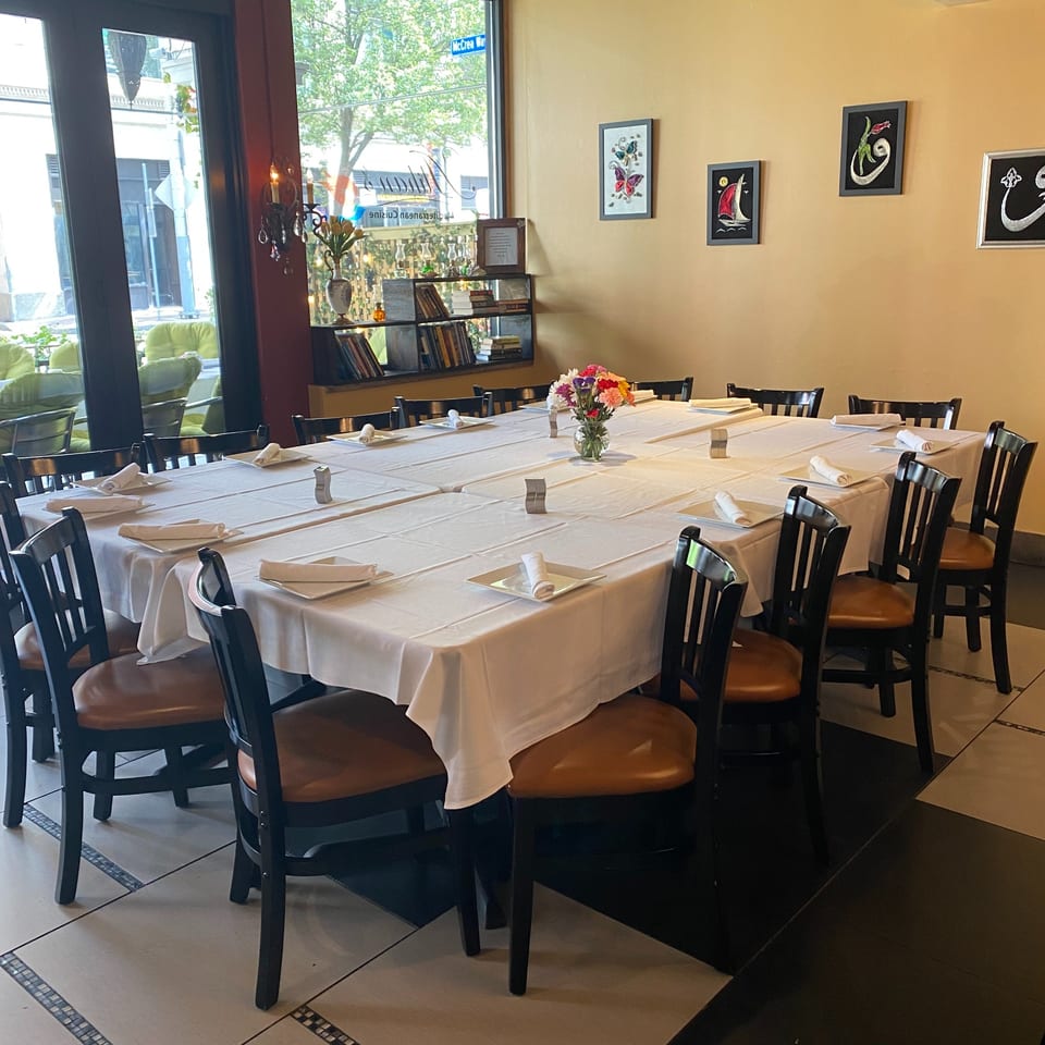 A long dining table with white tablecloths and dark chairs, set for a large group.