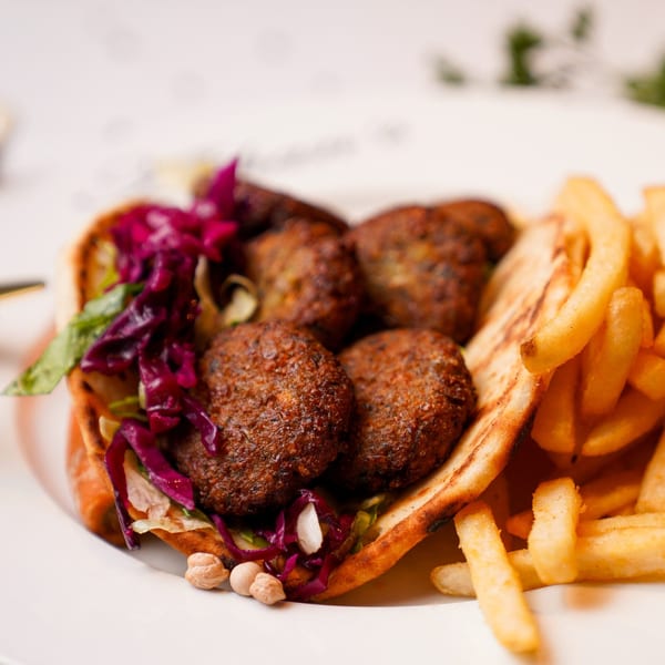 Alihan's falafel pita with red cabbage, lettuce, chickpeas, and a side of golden french fries.
