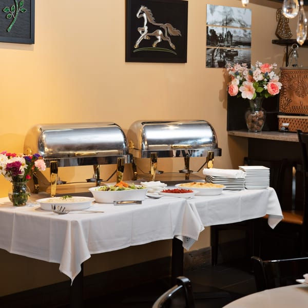 A buffet table with chafing dishes, salads, and Mediterranean appetizers at Alihan's Cuisine.