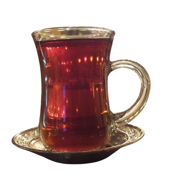A glass of Alihan's Mediterranean black tea in a traditional clear mug with a silver saucer.