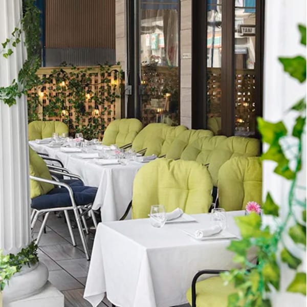 Outdoor dining area at Alihan's Mediterranean Cuisine with set tables, green cushions, and ivy decorations.