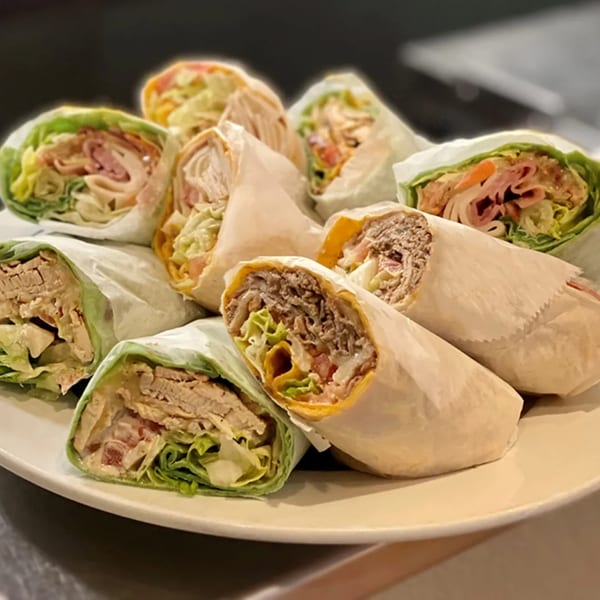 A platter of various Alihan's Mediterranean Cuisine wraps, some in lettuce, some in tortillas.