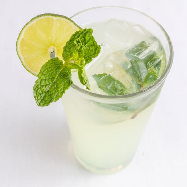 Refreshing Mediterranean drink with lime and mint garnish, served in a tall glass with ice.