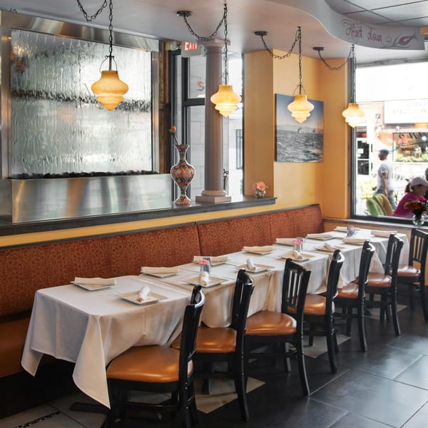 Interior of Alihan's Mediterranean Cuisine with set tables, a water wall, and warm lighting.