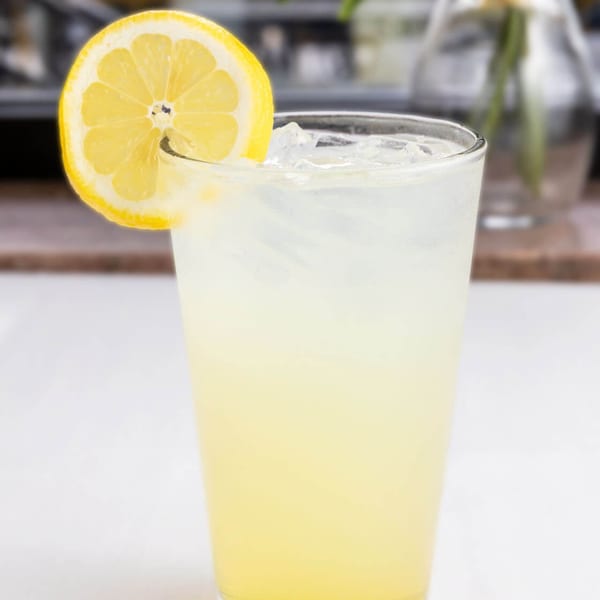 A refreshing glass of lemonade with ice and a lemon slice, perfect for Alihan's Mediterranean Cuisine.