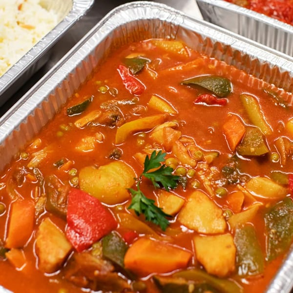 Alihan's Mediterranean Cuisine vegetable stew with potatoes, peppers, and peas in a foil container.